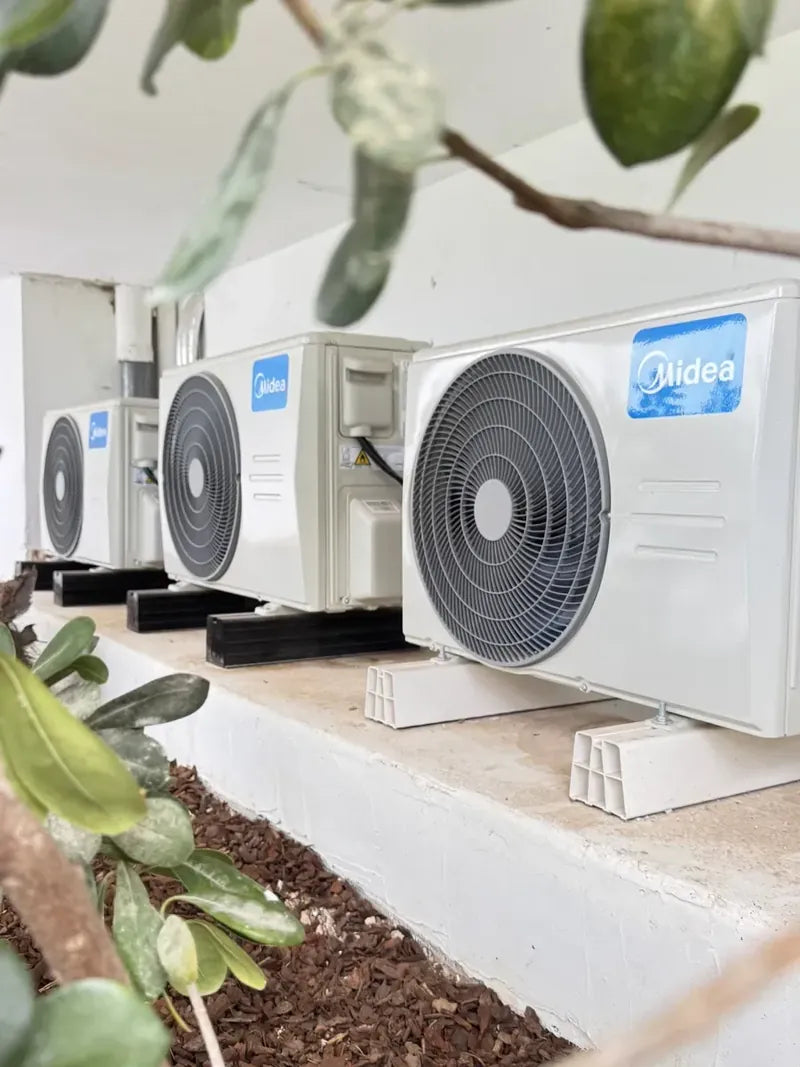 Tres unidades exteriores multi split sobre poyete encalado entre olivos
